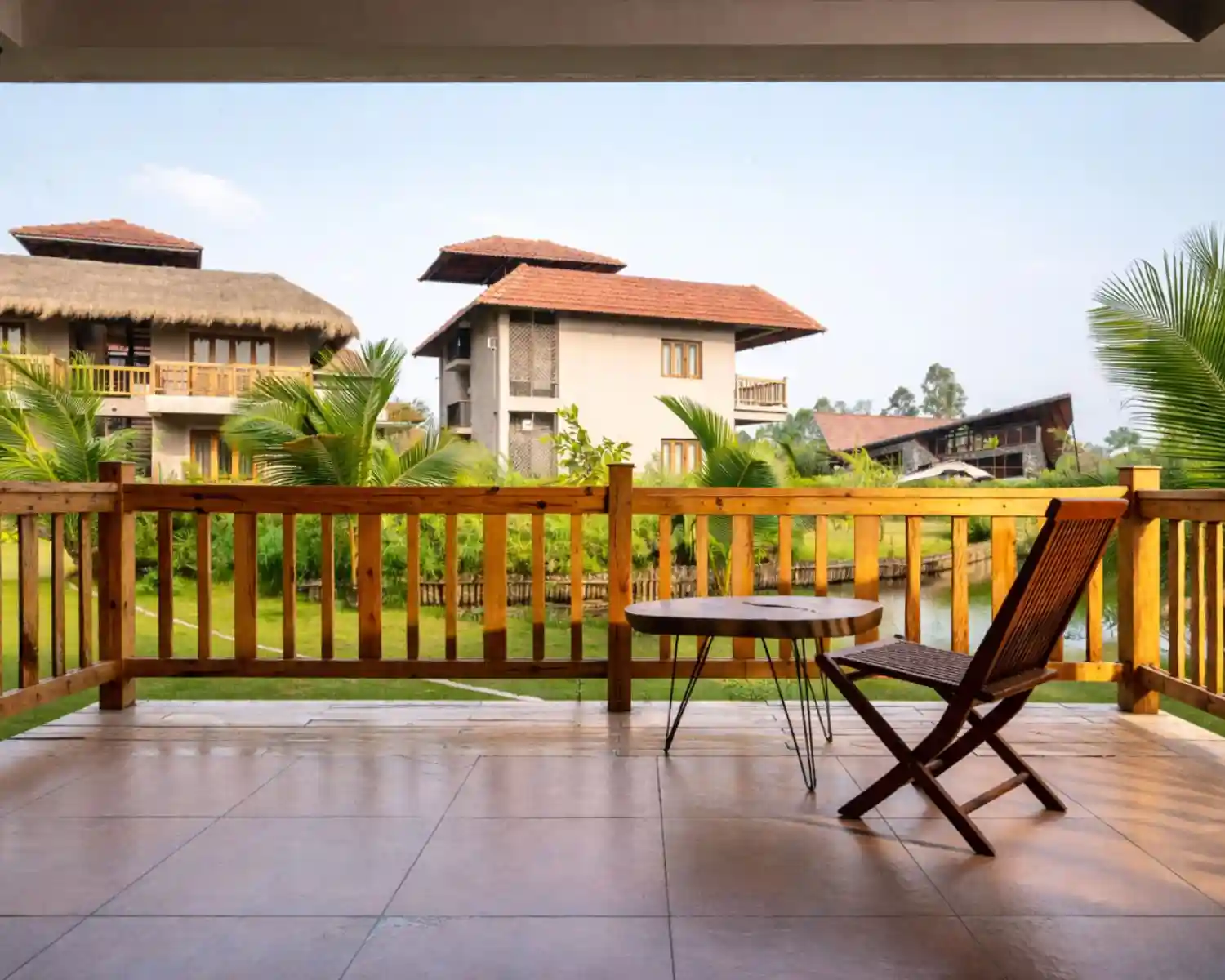 Luxury balcony sitting area at Hotel Sonar Bangla Sundarban resort with garden and cottage view.