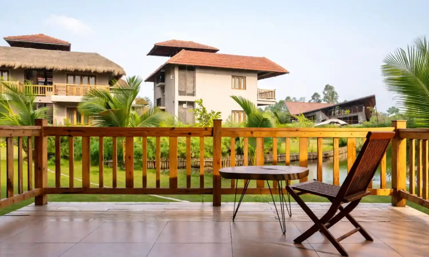 Luxury balcony sitting area at Hotel Sonar Bangla Sundarban resort with garden and cottage view.